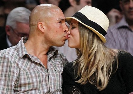 Actress Kaley Cuoco right kisses an unidentified man as they sit courtside 
